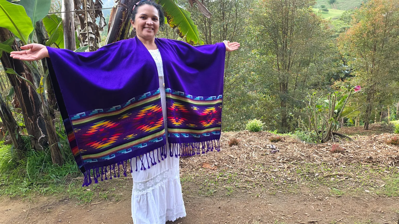 Andrea Díaz standing outdoors in a purple woven poncho at Camino al Sol